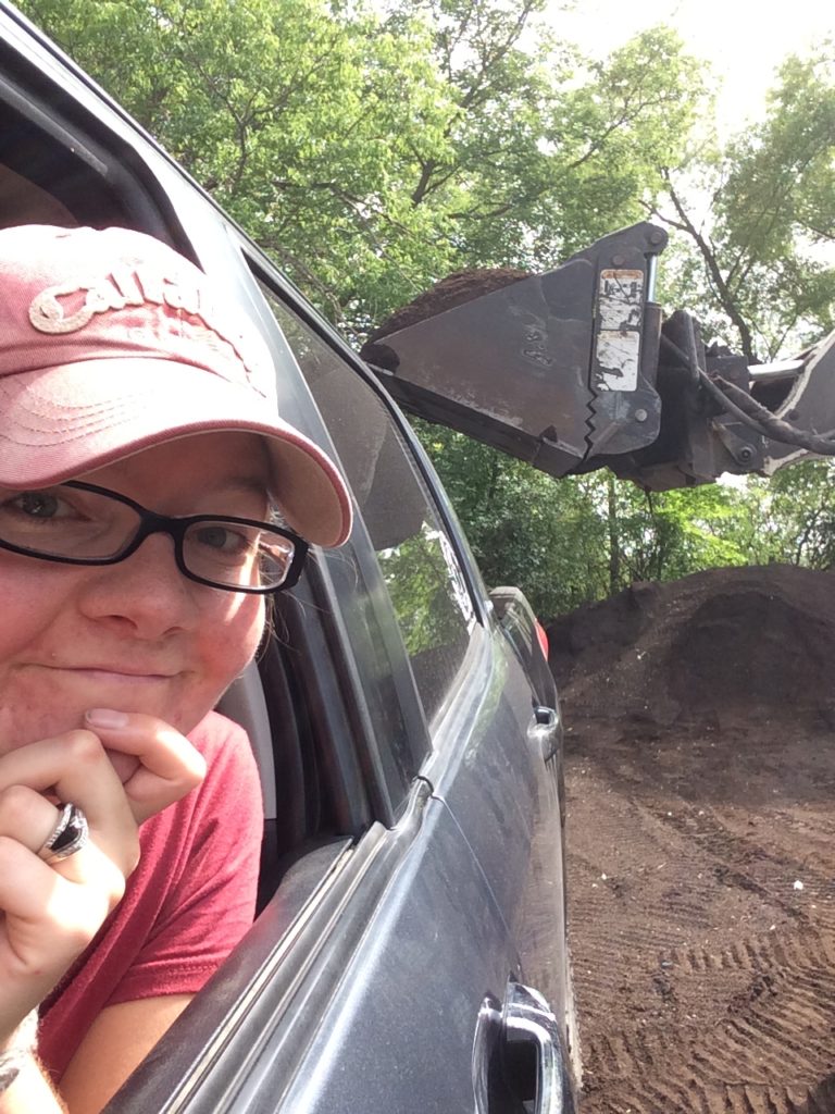 Skidsteer loading organic soil into back of women's truck