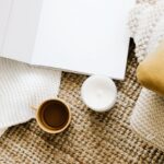 opened diary placed on table near mug and candle