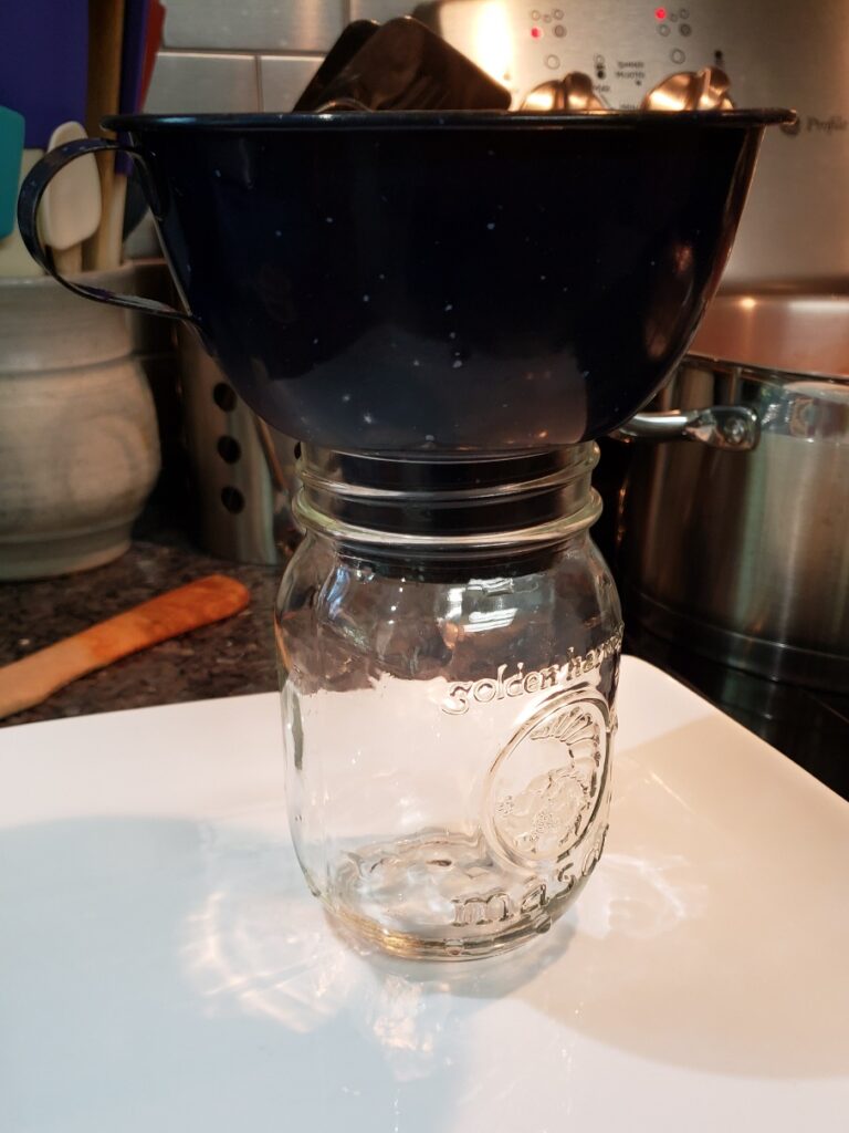 Mason jar with funnel on top, waiting to be filled with hot food to can