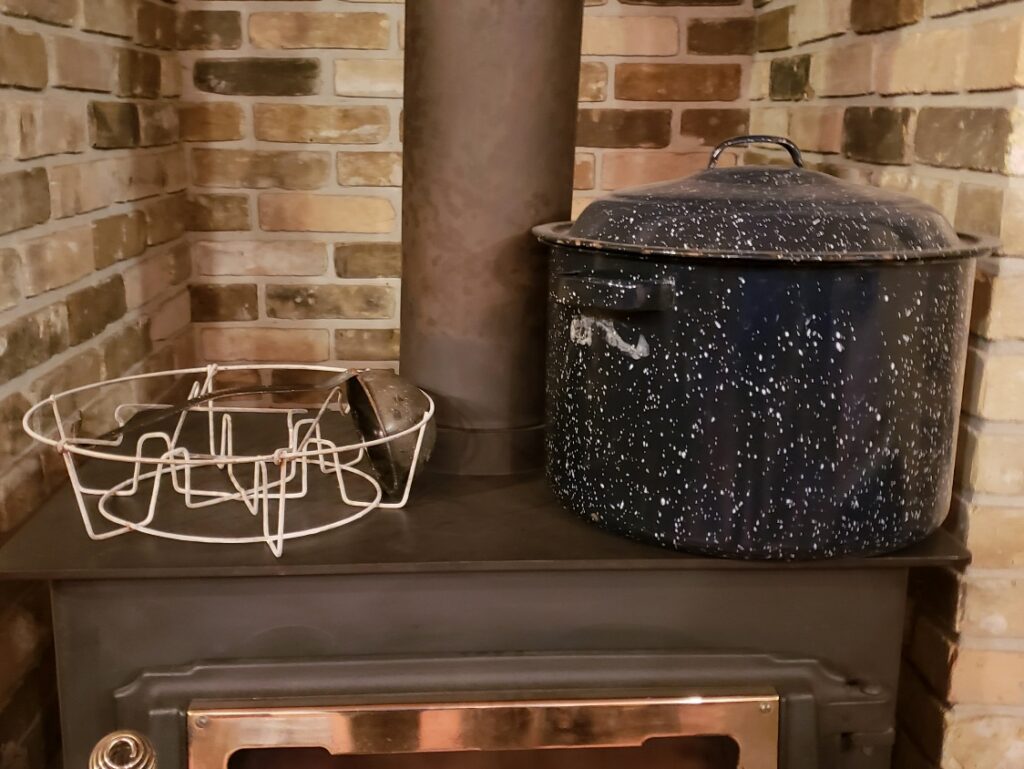 Water bath canner and rack insert sitting on a wood stove top